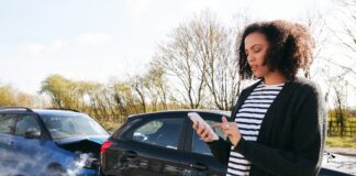 Female Driver Contacting Car Insurance Company On Mobile Phone After Road Traffic Accident