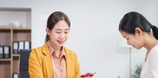 Asian businesswoman and a salesman discuss car sales, insurance, financing a customer at a desk