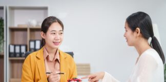 Asian businesswoman and a salesman discuss car sales, insurance, financing a customer at a desk