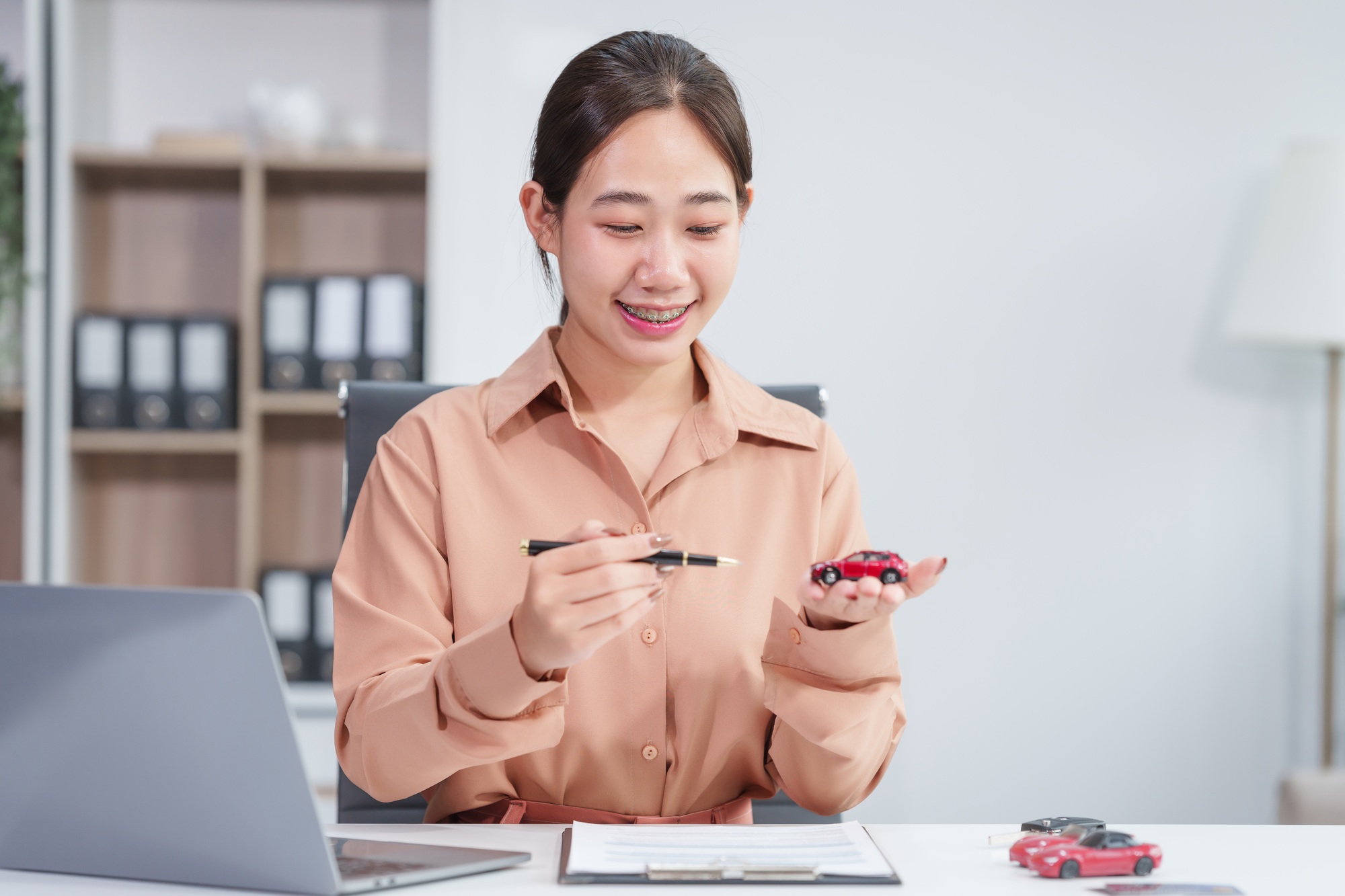 Asian businesswoman negotiates the sale of a car, discussing insurance and financing options