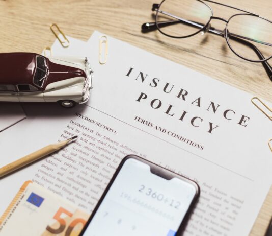 Flat lay of vehicle insurance policy. Magnifier, retro car toy and cash