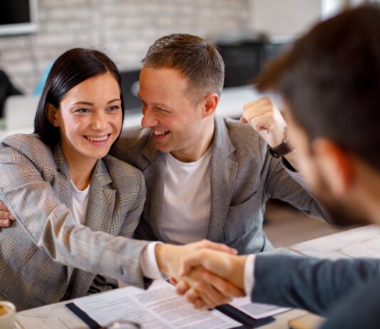 Happy young couple make a deal with their personal financial advisor in bank