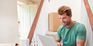 Man Moving Into New Home Looking At Personal Finances On Laptop