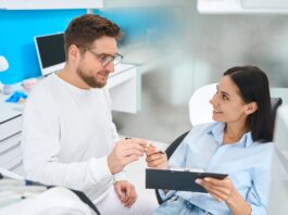 Professional stomatologist offering to sign insurance documents to female patient